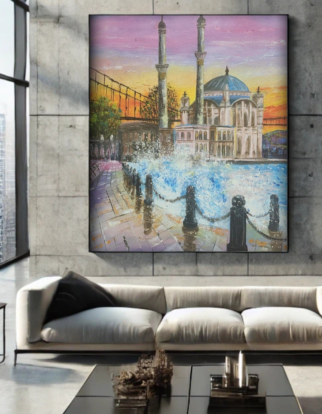 A vibrant painting capturing the Ortaköy Mosque and the Bosphorus with a dynamic sunset sky and reflecting water. Waves crashing on the shore. Painting hanging over a grey sofa on a concrete wall.