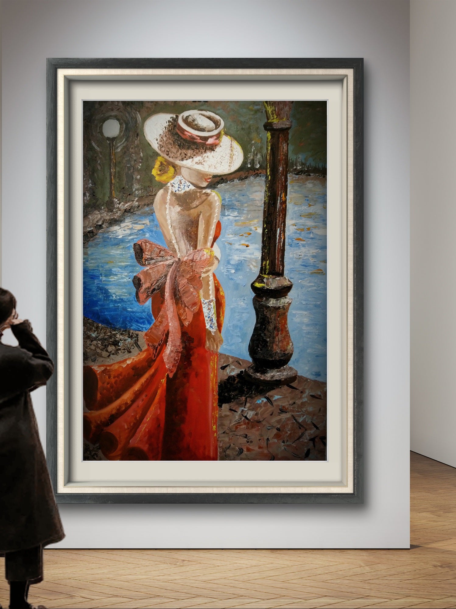 Framed artwork of a woman in a red dress and white hat by a body of water, with a person observing it.