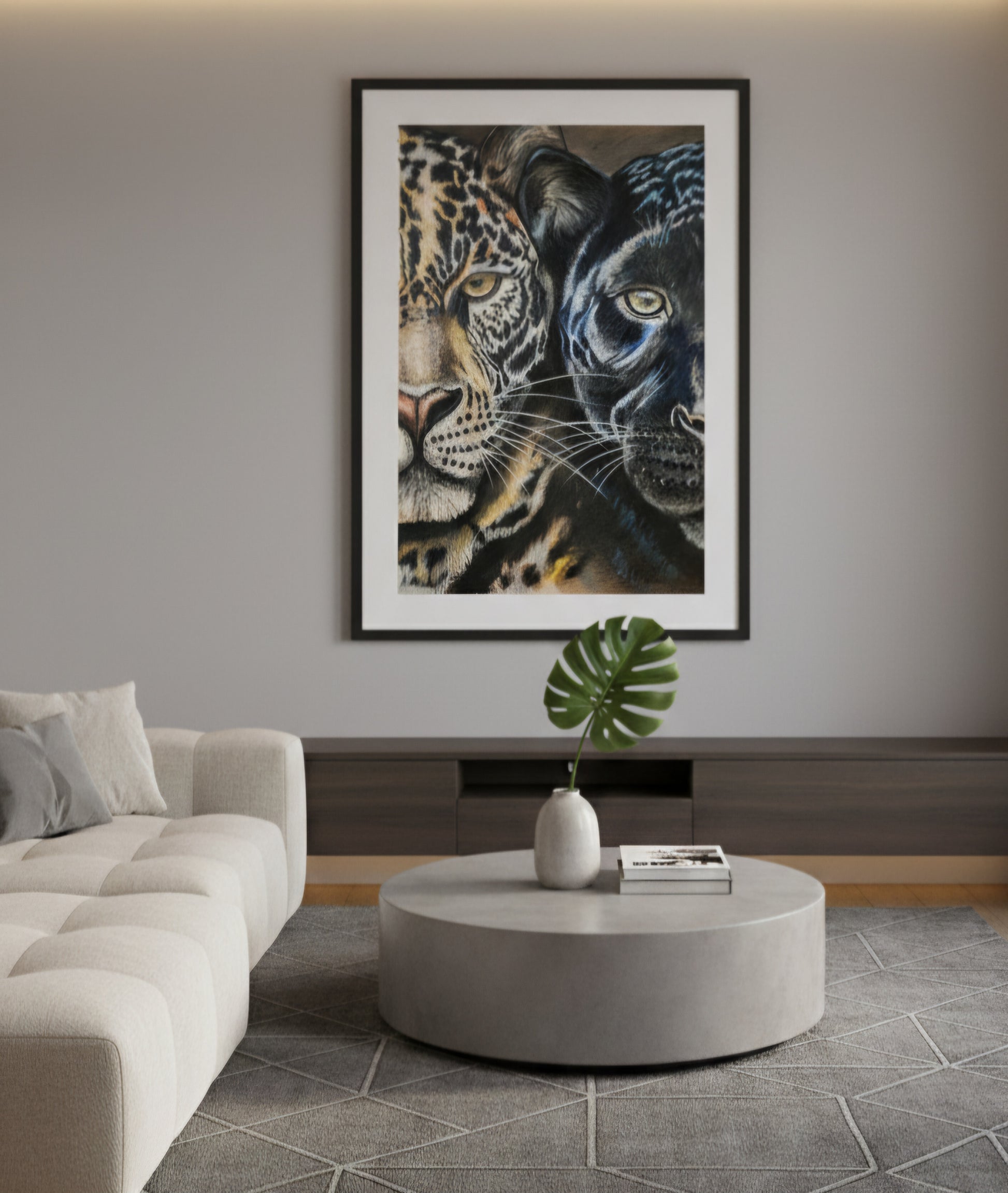 Living room with a large framed picture of two leopards on the wall, a round coffee table with a plant and books, and a beige sofa.