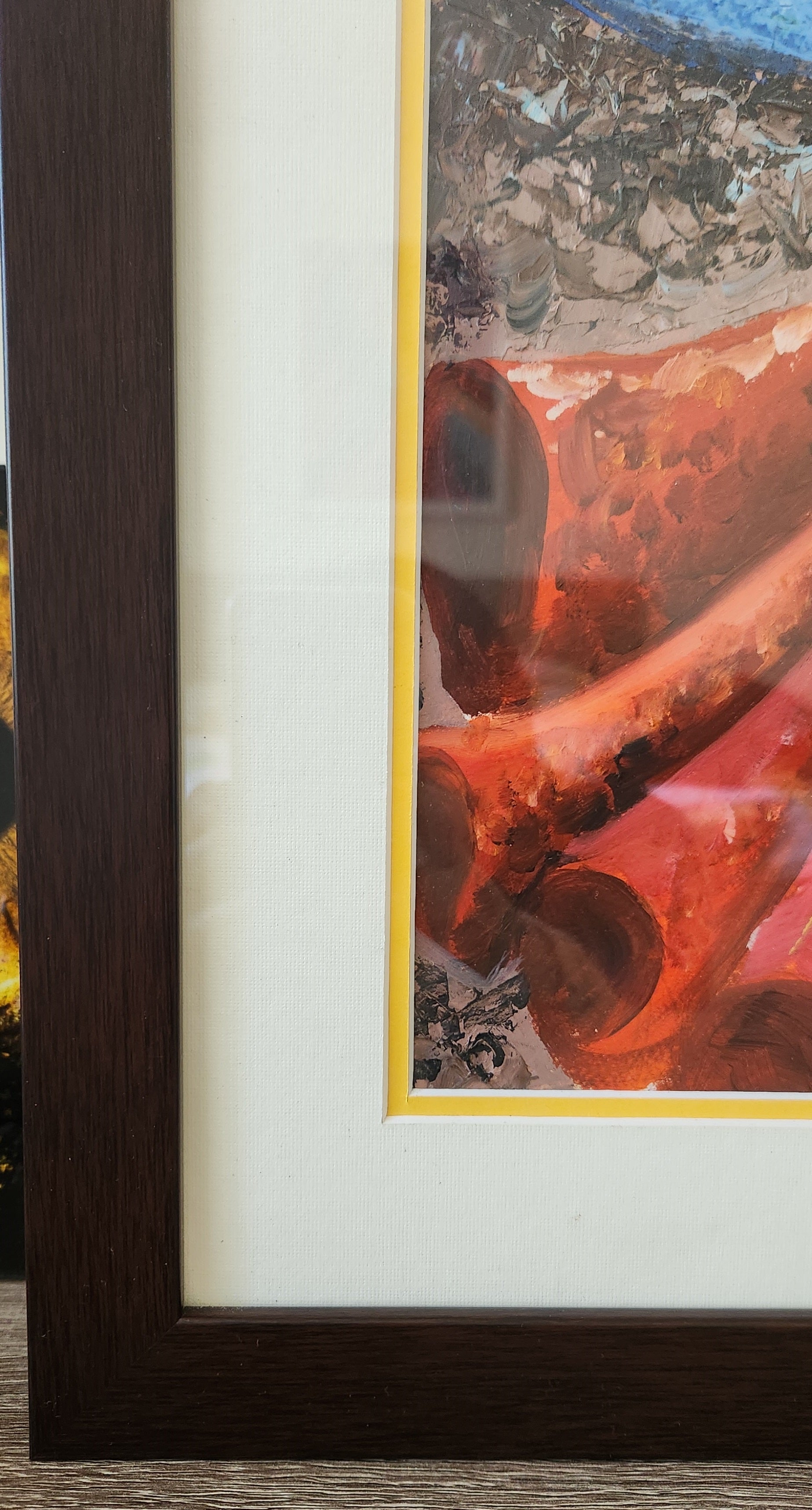 Framed artwork with a dark wooden border and a colorful abstract design.